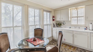 A dining area with a glass table, chairs, and a ceiling fan. - Carriage Inn - Tarpley Suite 5 (Bandera)