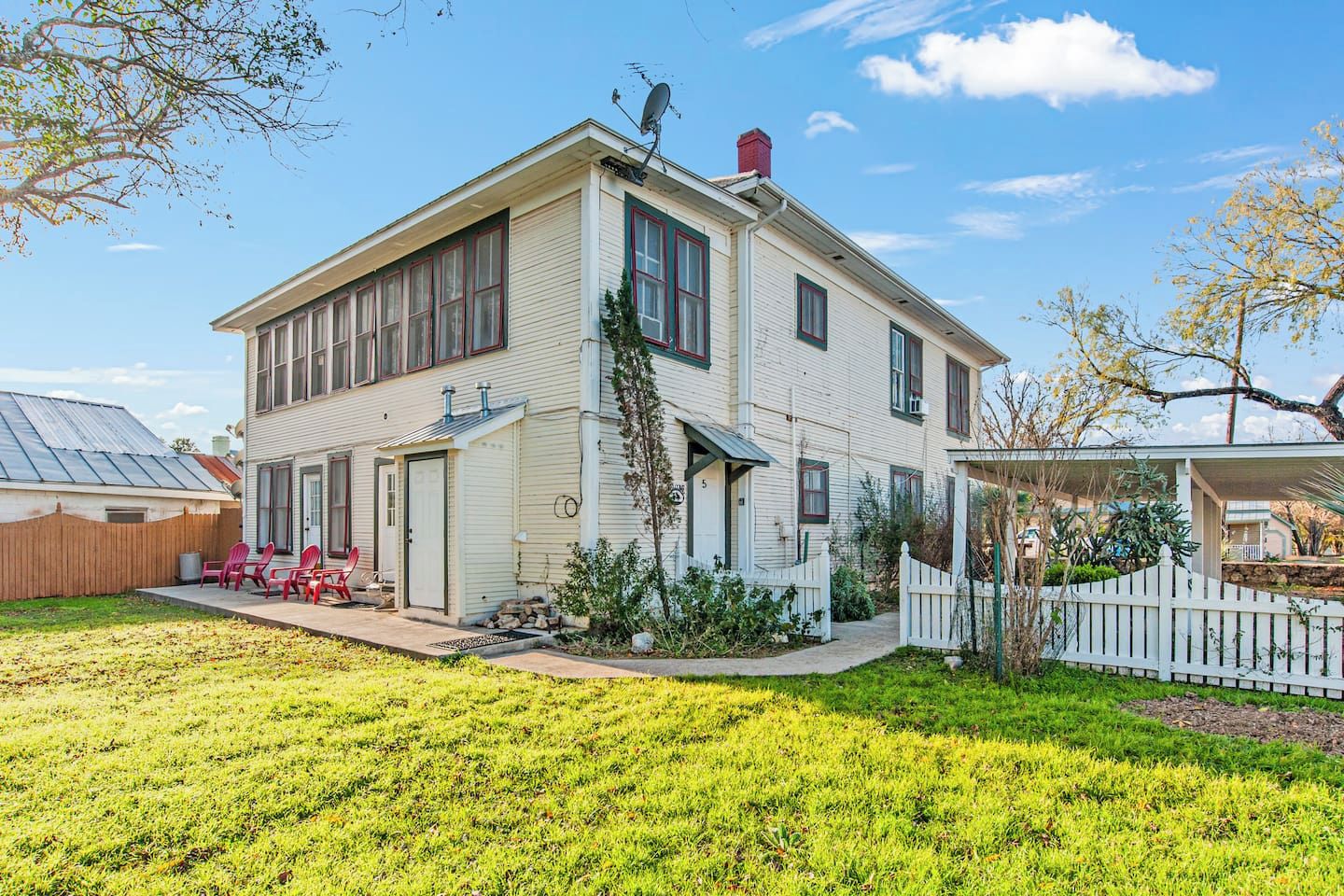 A two-story house with a front porch, a small attached garage, and a fenced yard.