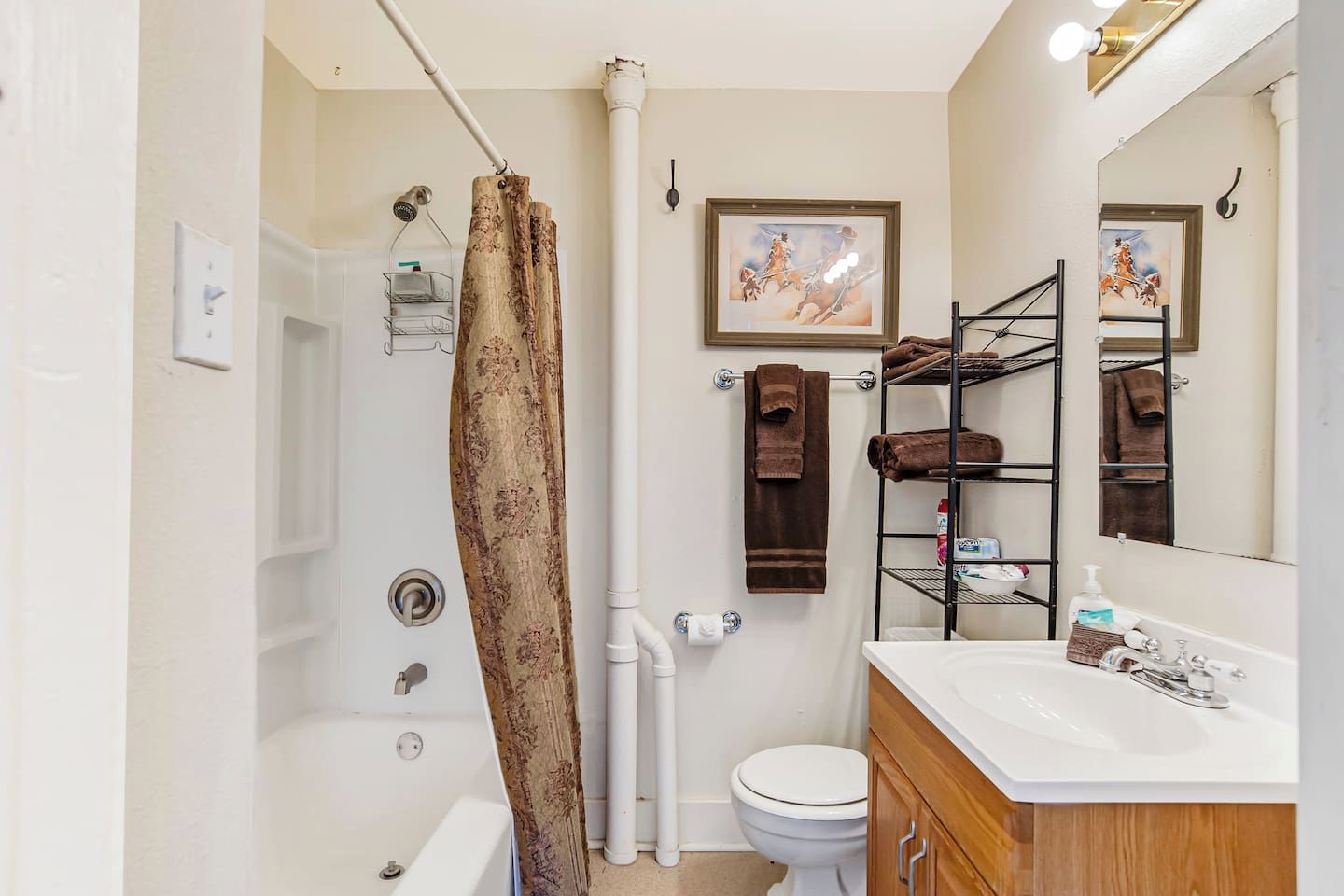 A bathroom with a shower curtain, toilet, sink, and towel rack.