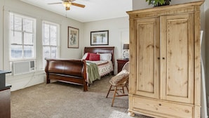 A bedroom with a wooden bed, a wooden wardrobe, and a ceiling fan. - Carriage Inn - Tarpley Suite 5 (Bandera)