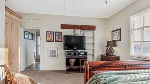 A bedroom with a bed, a TV, a wooden cabinet, and a window with blinds. - Carriage Tarpley 5 | Queen Suite w/ Kitchen (Bandera)