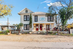 A two-story building with a porch, a red door, and a sign that reads 'Carriage House Inn.'