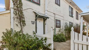 A white wooden building with a 'WELCOME' sign, a number '5' on the door, and a white picket fence. - Carriage Inn - Tarpley Suite 5 (Bandera)