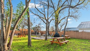 A backyard with picnic tables, a barbecue grill, and a stone fireplace. - Carriage Tarpley 5 | Queen Suite w/ Kitchen (Bandera)