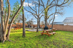 A backyard with picnic tables, a barbecue grill, and a stone fireplace. - Carriage Tarpley 5 | Queen Suite w/ Kitchen (Bandera)