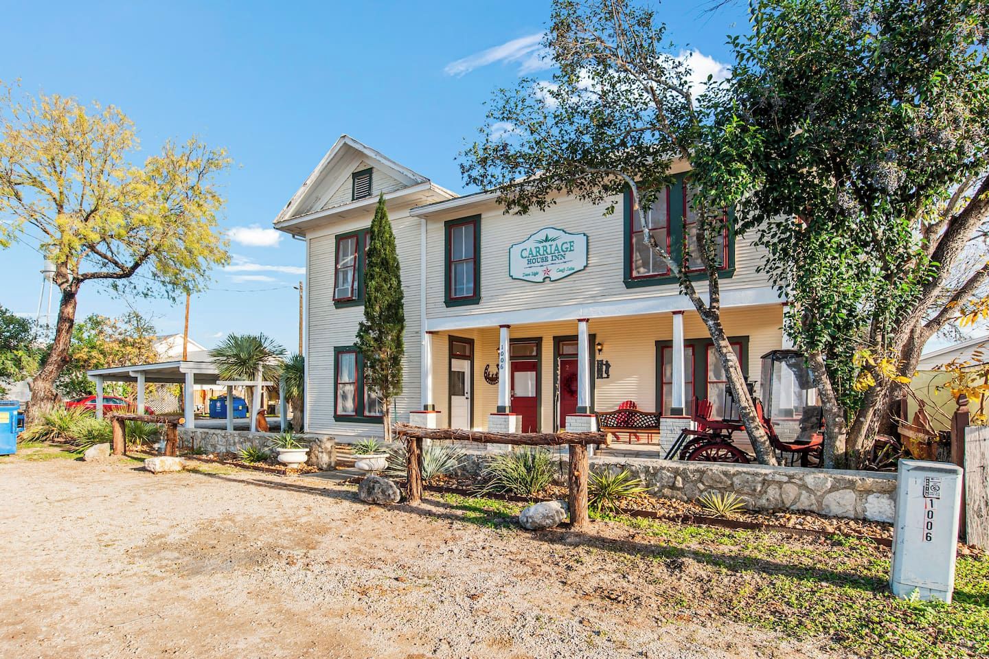 A two-story building with a porch and a sign that reads 'Carriage House Inn.'