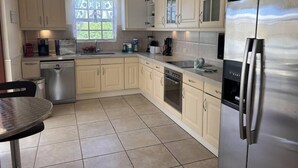 Una cocina moderna con armarios de tonos claros, un refrigerador de acero inoxidable y un lavavajillas.