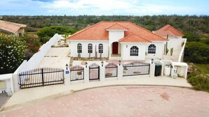 Un edificio blanco con tejado de tejas rojas, ventanas arqueadas y una entrada con portón.