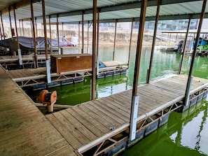 Un muelle de madera con un bote y una bomba de agua.
