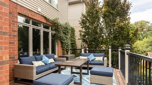 Un patio couvert aménagé avec des meubles en osier et un tapis à motifs.