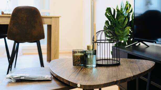 Une table en bois avec un verre, une bougie et une petite plante. Une télévision se trouve sur le côté droit.