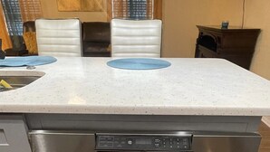 A kitchen with a built-in oven and microwave, grey cabinets, and a white countertop.