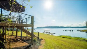 A lakeside property with a wooden deck and stairs leading to a covered area. - Douglas Lake -LakeFRONT home w/ Dock (Dandridge)