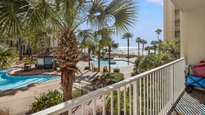 A pool area with palm trees and a view of the beach.