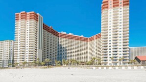 A high-rise hotel with multiple floors, a prominent central tower, and a beachside location.
