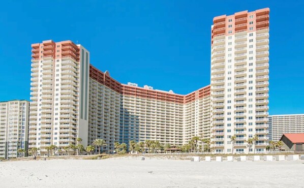 A high-rise hotel with multiple floors, a prominent central tower, and a beachside location.