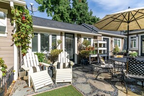 Un patio con sillas Adirondack, una mesa y una sombrilla.