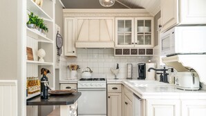 A kitchen with white cabinetry, a stove, a sink, and various kitchen appliances.