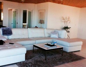 Uma sala de estar moderna com um sofá seccional, uma mesa de centro e uma luminária.