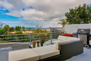 Terraço no telhado com sofá, churrasqueira e vista para a paisagem.