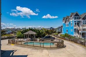 A residential area with a swimming pool, a gazebo, and a blue house.