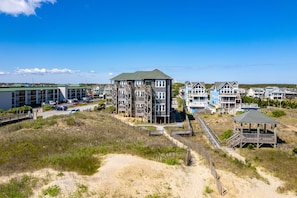 A coastal residential area with multi-story buildings, a sandy beach, and a wooden boardwalk.