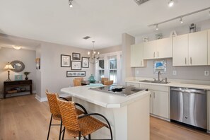 A modern kitchen with a central island, stainless steel appliances, and a dining area with wicker chairs.