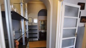 A hallway with a wooden floor, a white door with frosted glass panels, and shelves with various items. - Penthouse in cit turin (Torino)