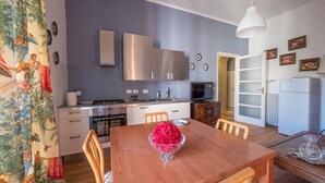 A compact kitchen with modern appliances, a dining area with a wooden table and chairs, and a living area with a sofa and a TV. - Penthouse in cit turin (Torino)