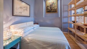 A bedroom with a bed, a nightstand, a shelf with decorative items, and two framed artworks on the wall. - Penthouse in cit turin (Torino)
