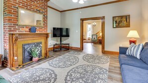 A living room with a fireplace, television, and a blue sofa. - Mtn Views & Idyllic Setting! Clifton Forge Retreat (Clifton Forge)