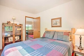 Un dormitorio con una cama grande, un aparador de madera con puertas de cristal, un cuadro en la pared y una lámpara sobre una mesita de noche.