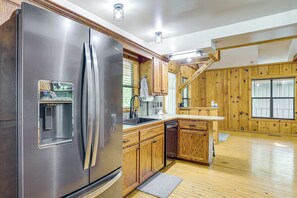 Una cocina moderna con electrodomésticos de acero inoxidable, armarios de madera y piso de madera.