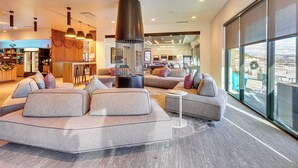 A modern hotel lobby with a large sectional sofa, a fireplace, and a view of the outdoors through large windows. - Walk to Gondola: 'Love at Frost Sight' Ski Condo (Park City)