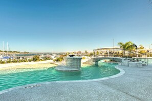 A waterfront swimming pool with a central fountain, a bridge, and a view of boats and buildings in the background. - Lakeside Montgomery Condo Near Boat Rental! (Montgomery)