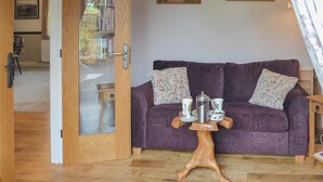 Une pièce avec un canapé violet, une table basse en bois et deux tableaux accrochés au mur.