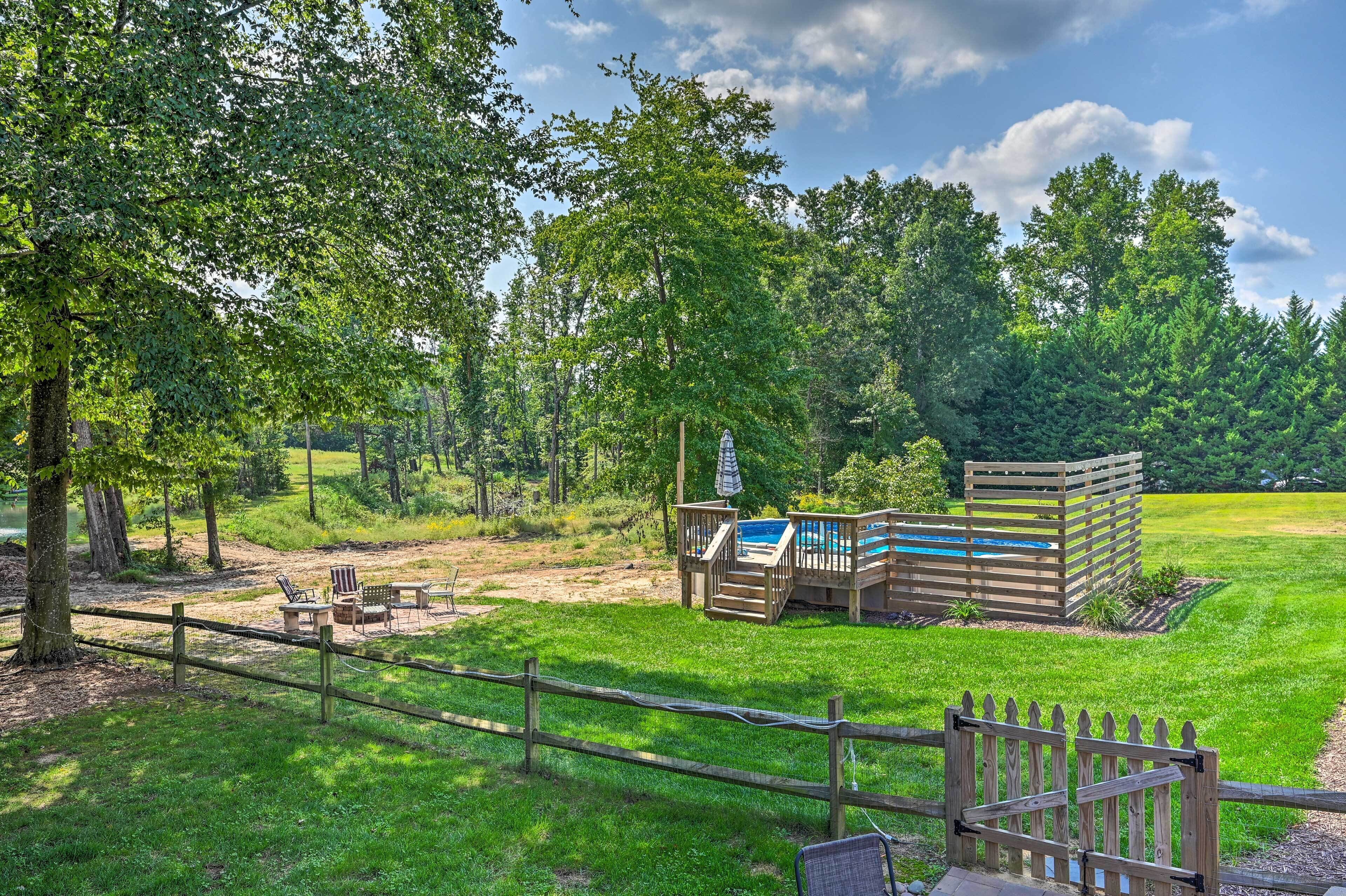 A wooden deck with a pool, surrounded by a fenced area with chairs and a table.