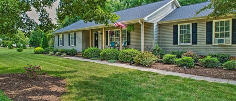 A two-story house with a covered porch, a small garden, and a well-maintained lawn.