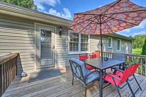 A deck with a table and chairs, a red umbrella, and a house with a porch. - Peaceful Country Retreat w/ Easy Highway Access! (Browns Summit)