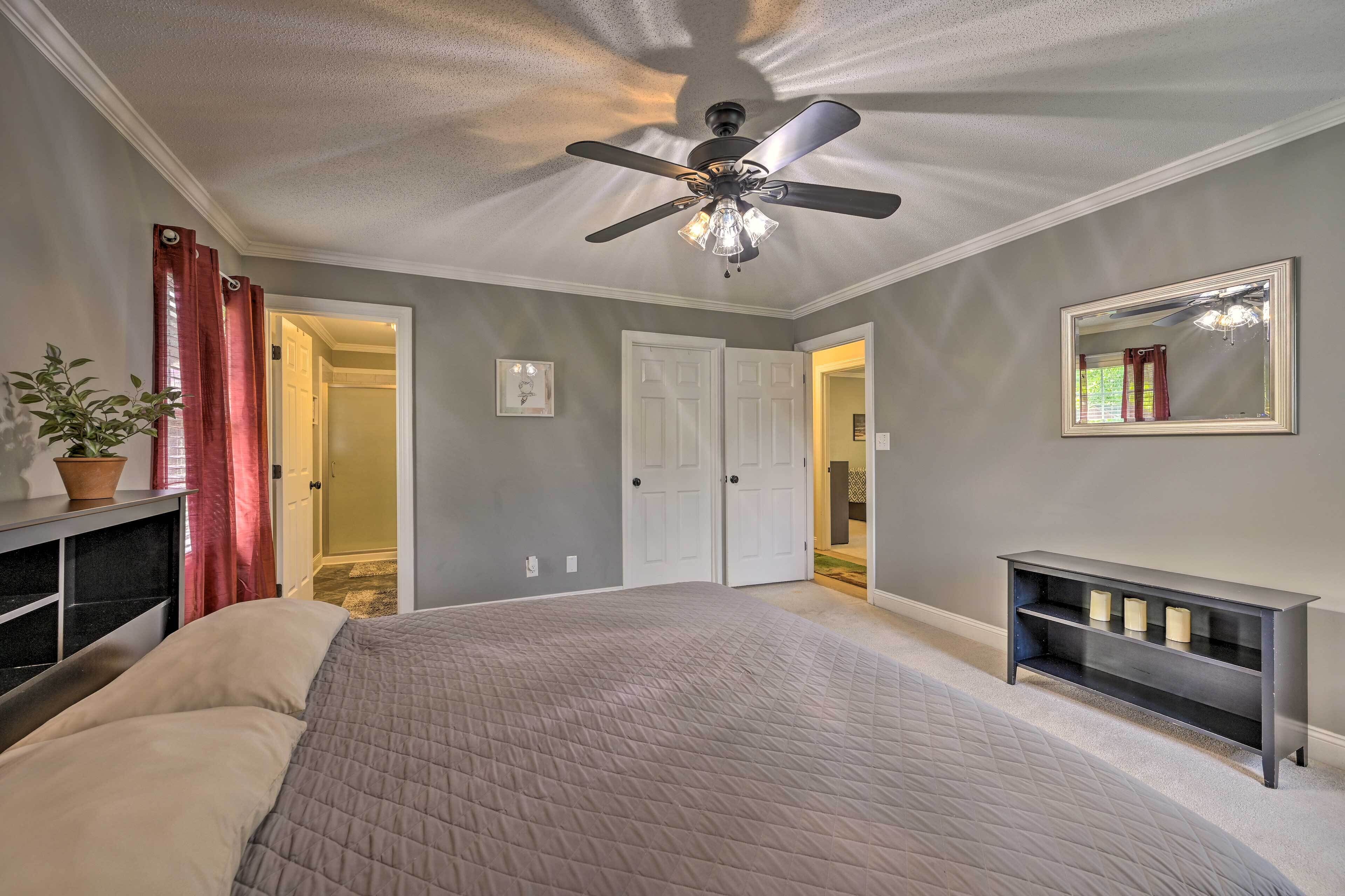 Quarto com cama, ventilador de teto e mesa consola com velas.