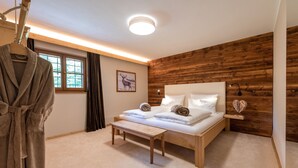 Ein Schlafzimmer mit einem hölzernen Kopfteil, einem Bett mit weißer Bettwäsche, einem Nachttisch und einem aufhängbaren Bademantel.