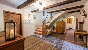 Ein rustikales Interieur mit einer Holztreppe, Steinböden und einer hölzernen Bank.