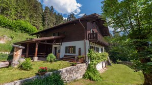 Eine rustikale Chalet mit Holzfassade, einem Balkon und einem Steingarten.