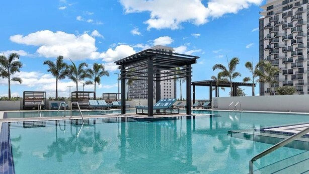 A rooftop swimming pool with lounge chairs and a gazebo. - Luxury Condo - 3B/3B with Amazing Skyline View (Doral)