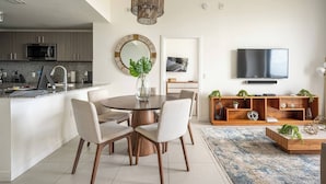 A modern kitchen with a dining area, a TV, and a wooden console. - Luxury Condo - 3B/3B with Amazing Skyline View (Doral)
