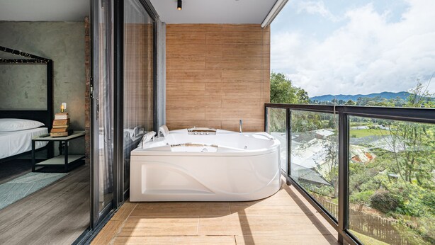 Un baño moderno con una bañera grande, cabina de ducha de vidrio y pared de madera.