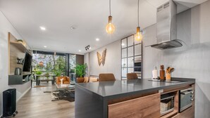 Una cocina moderna con una isla central, armarios de madera e iluminación colgante.