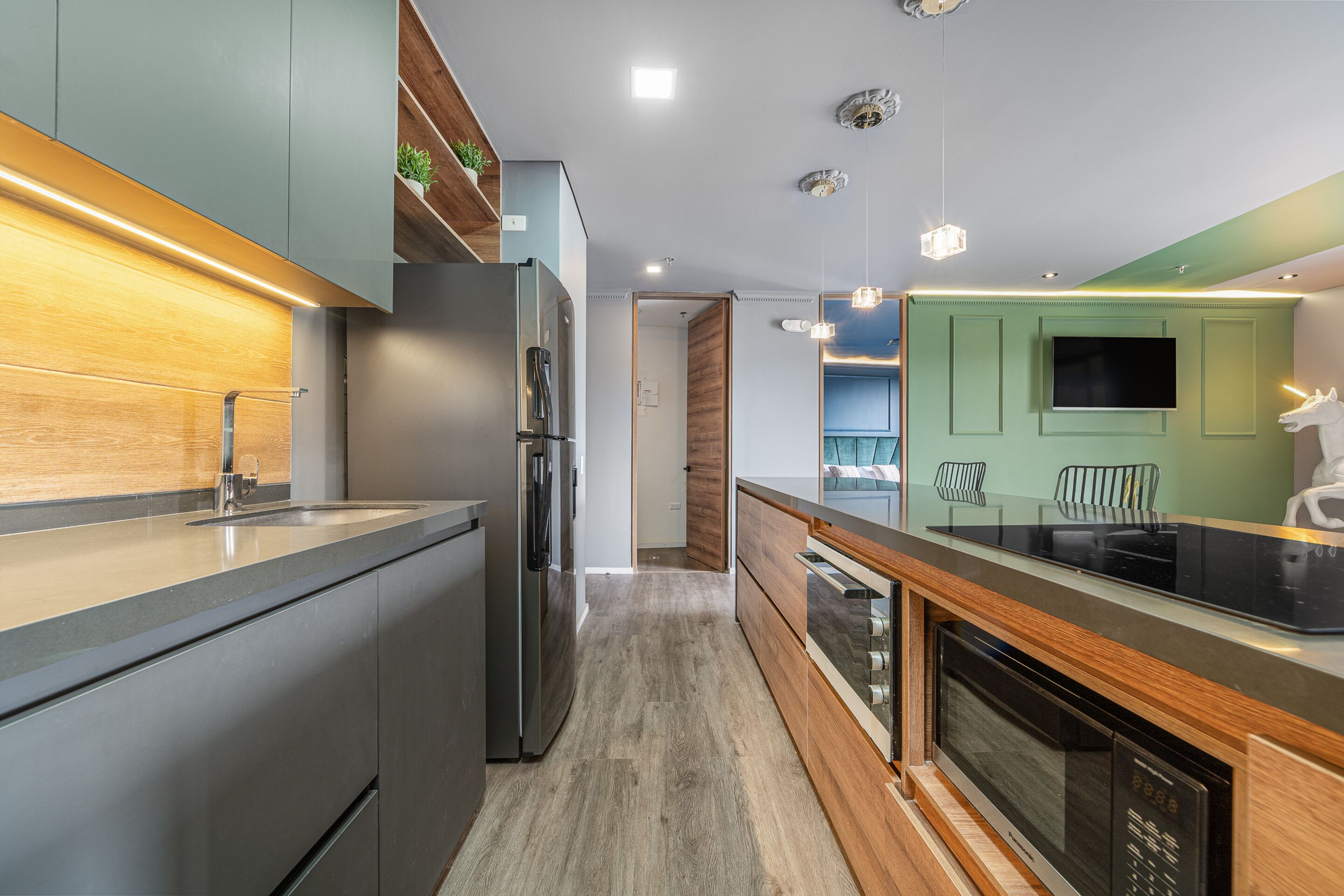 Une cuisine moderne dotée d’un réfrigérateur en acier inoxydable, de meubles en bois, d’un four encastré et d’un grand îlot central avec un évier.