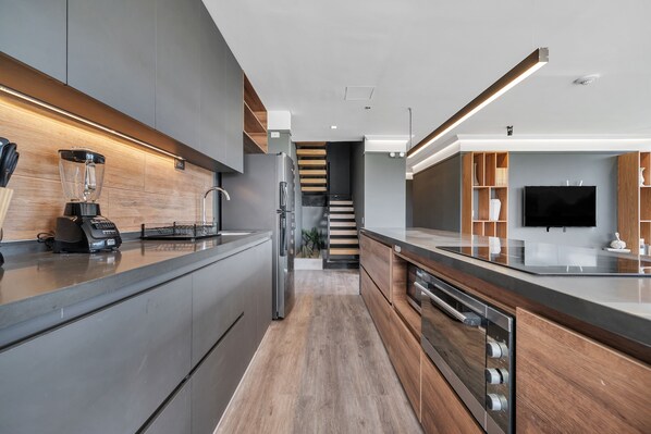 A modern kitchen with a central island, stainless steel appliances, and a wooden accent wall.
