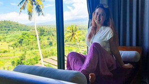 A person sitting by a window with a view of a green landscape. - A Romantic Gateaway Villa With The Best View Of Bali (Kabupaten Karangasem)
